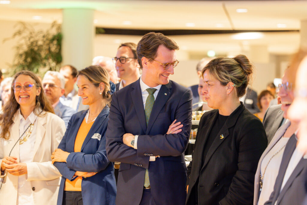 Ein Mann im Anzug im Gespräch mit einer schwarz gekleideten Frau 