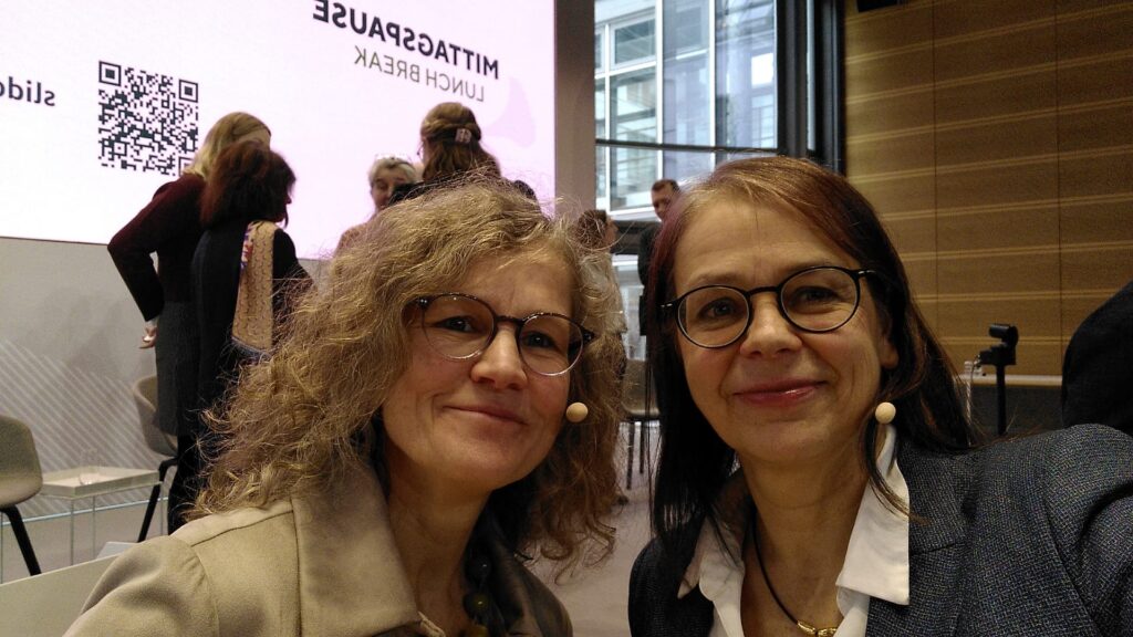 Zwei Frauen vor einer Bühne lächeln in die Kamera